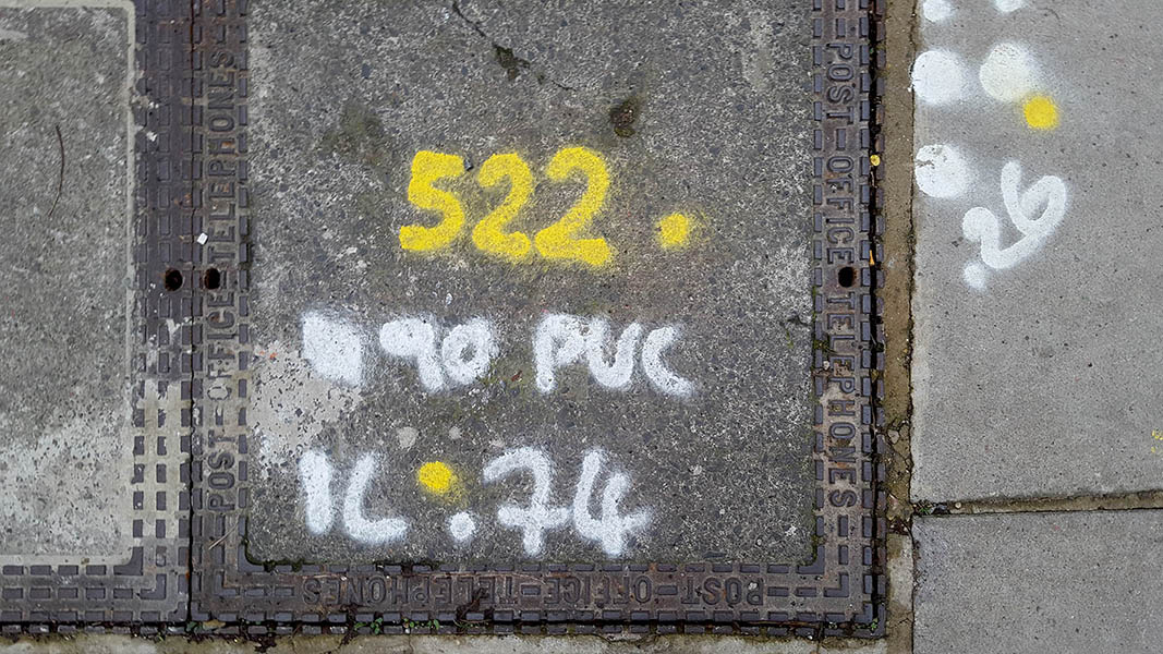 Pavement markings - spray painted squiggles on paving stones - Yellow and white numbers and letters
