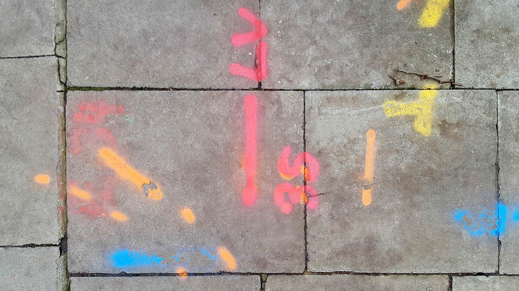 Pavement markings - spray painted squiggles on paving stones - Red orange blue yellow lines and numbers