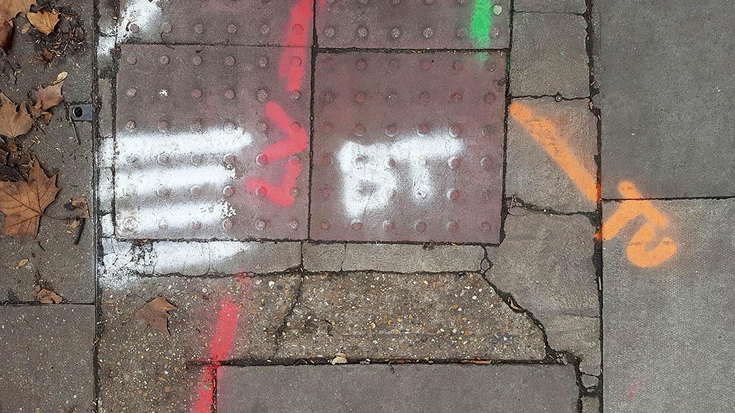 Pavement markings - spray painted squiggles on paving stones - White red orange lines and letters 