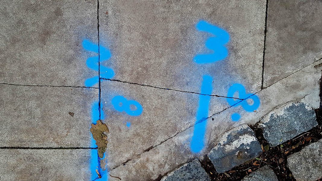 Pavement markings - spray painted squiggles on paving stones - Blue lines and letters