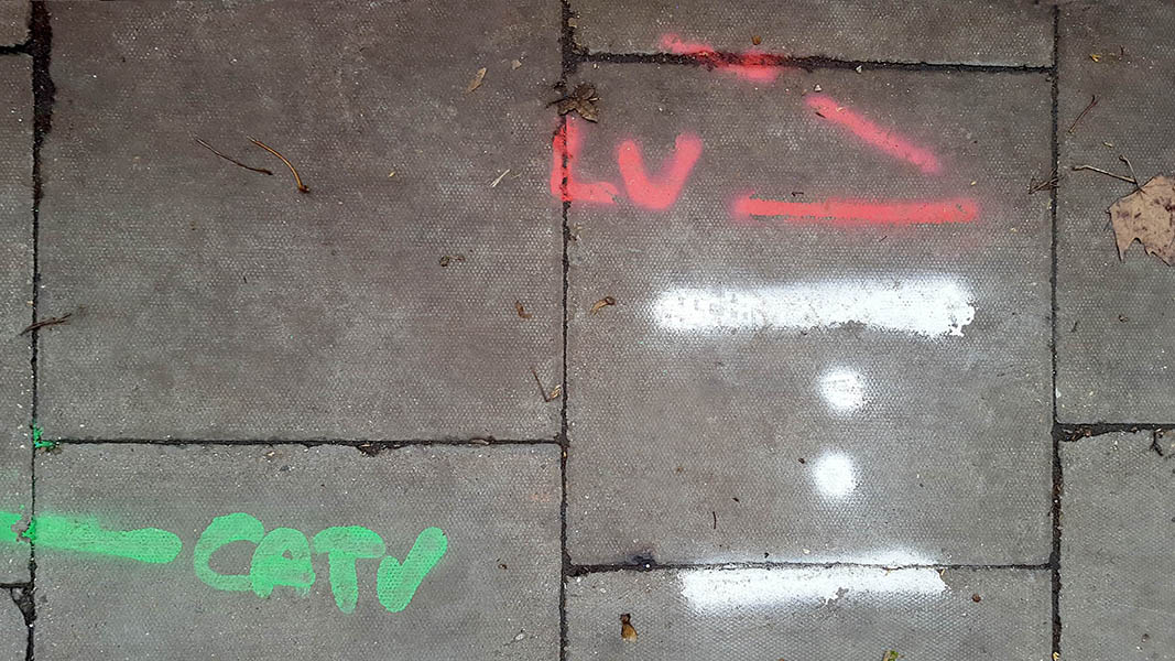 Pavement markings - spray painted squiggles on paving stones - Red white and green lines letters and dots