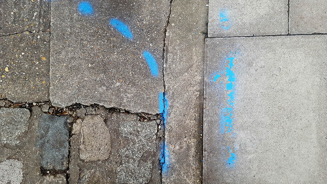 Pavement markings - spray painted squiggles on paving stones - Blue dashed lines