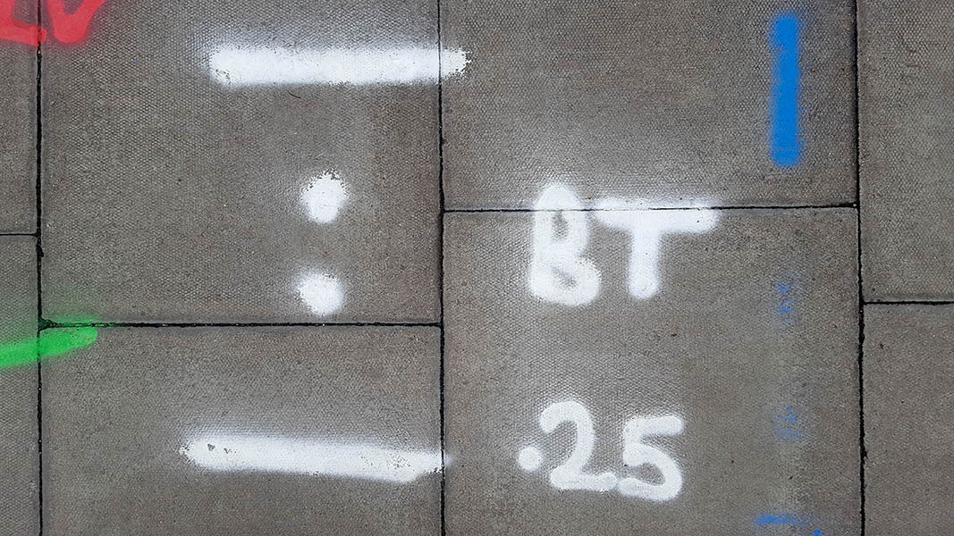 Pavement markings - spray painted squiggles on paving stones - White blue red green lines letters numbers and dots