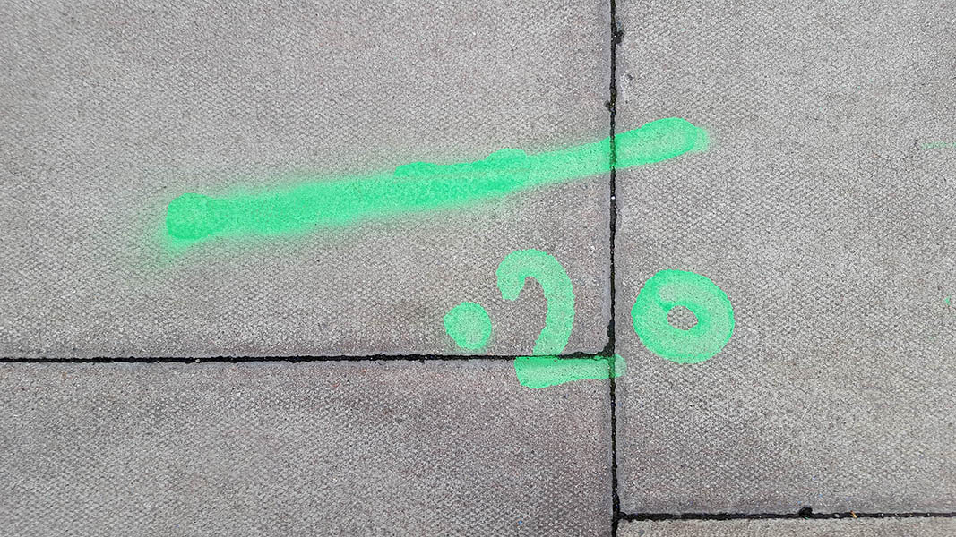 Pavement markings - spray painted squiggles on paving stones - Green line and numbers