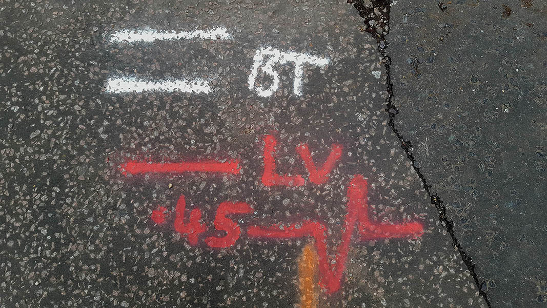 Pavement markings - spray painted squiggles on tarmac - White and red lines numbers and letters and heartbeat