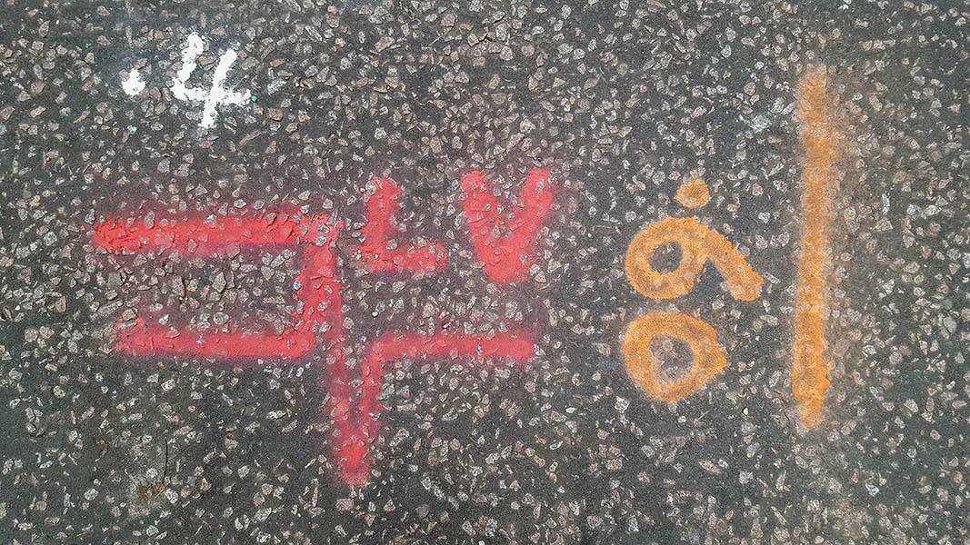 Pavement markings - spray painted squiggles on tarmac - Red orange white lines numbers letters and heartbeat