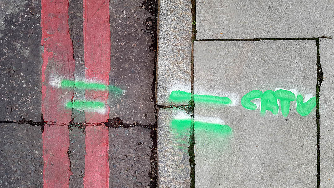 Pavement markings - spray painted squiggles on paving stones - Green lines and letters