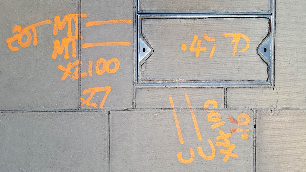 Pavement markings - spray painted squiggles on paving stones - Yellow lines and letters