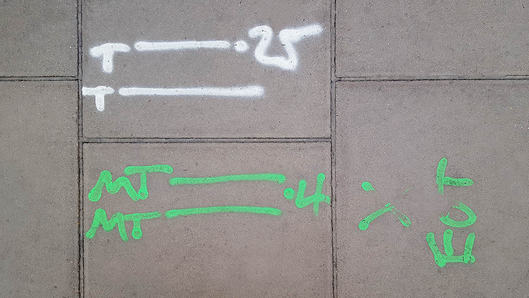 Pavement markings - spray painted squiggles on paving stones - White and green letters and lines