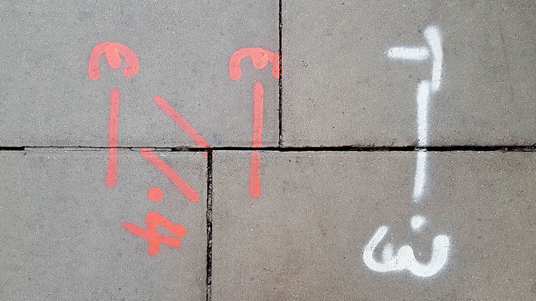 Pavement markings - spray painted squiggles on paving stones - White and red letters and words