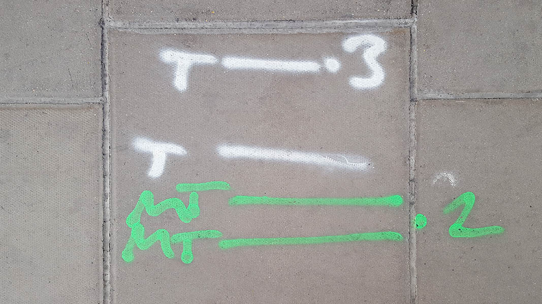Pavement markings - spray painted squiggles on paving stones - White and green letters and lines