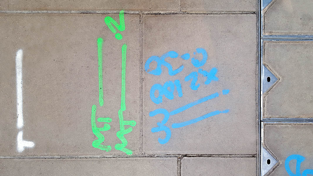 Pavement markings - spray painted squiggles on paving stones - White green and blue letters and lines