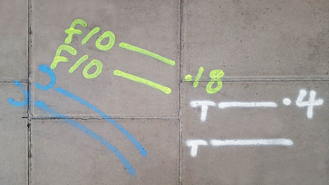 Pavement markings - spray painted squiggles on paving stones - White yellow and blue letters and lines