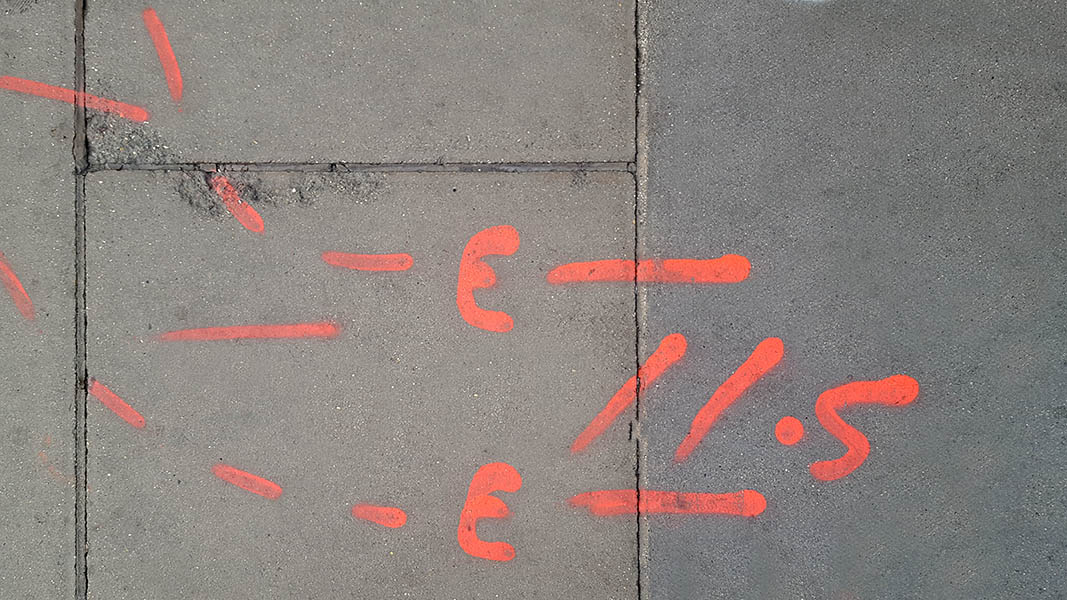 Pavement markings - spray painted squiggles on paving stones - Red letters and dashed lines
