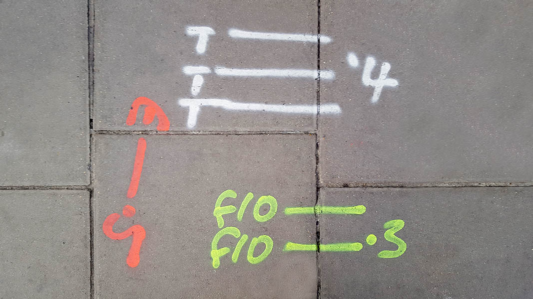 Pavement markings - spray painted squiggles on paving stones - White red and yellow letters and lines