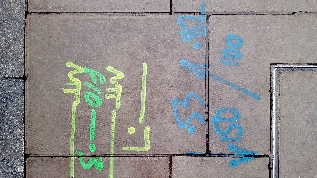 Pavement markings - spray painted squiggles on paving stones - Yellow green and blue letters and lines