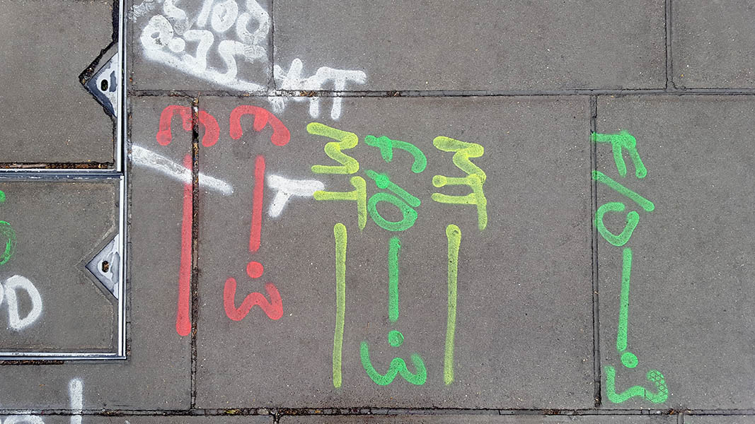 Pavement markings - spray painted squiggles on paving stones - Yellow green white and red letters and lines