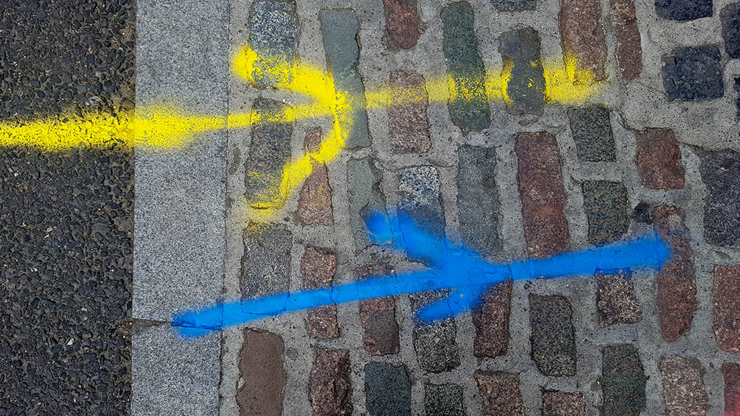 Pavement markings - spray painted squiggles on cobblestones - Yellow and blue lines with arrows