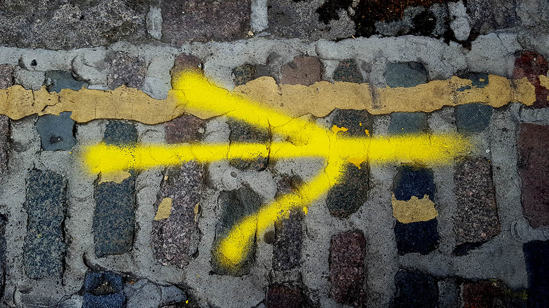 Pavement markings - spray painted squiggles on cobblestones - Yellow arrow