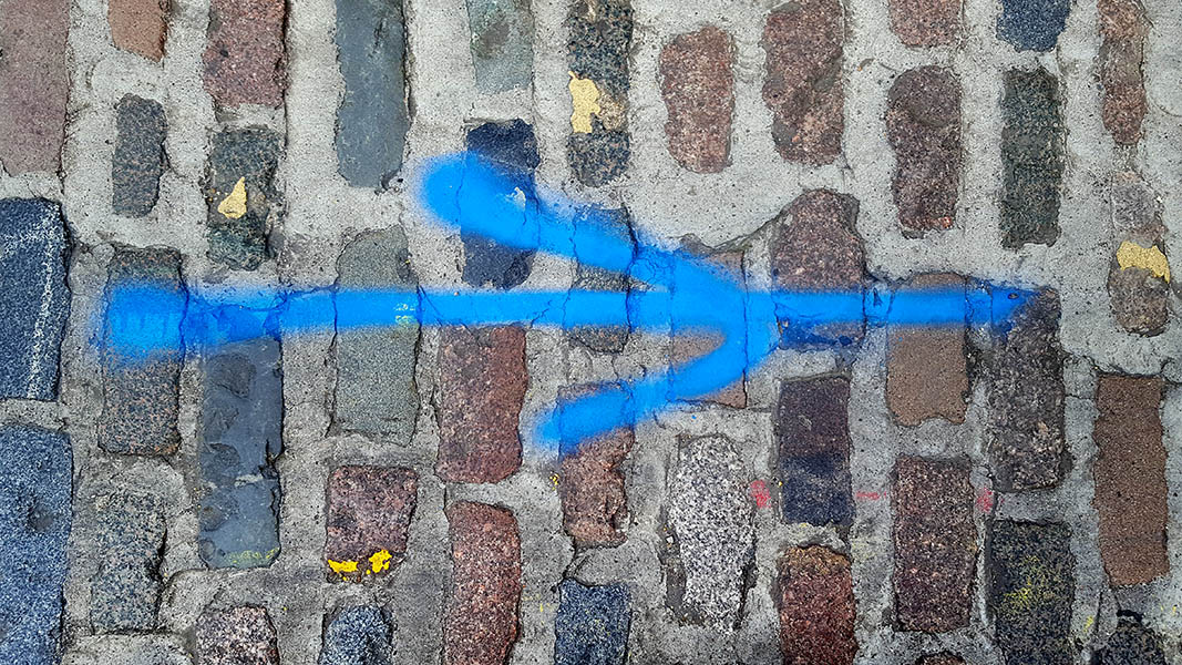 Pavement markings - spray painted squiggles on cobblestones - Blue arrow