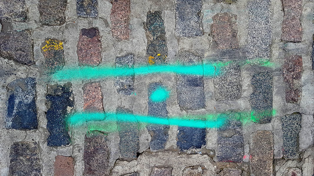 Pavement markings - spray painted squiggles on cobblestones - Two green stripes and a dot