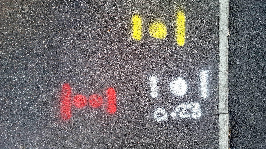 Pavement markings - spray painted squiggles on tarmac - Yellow white and red letters and lines