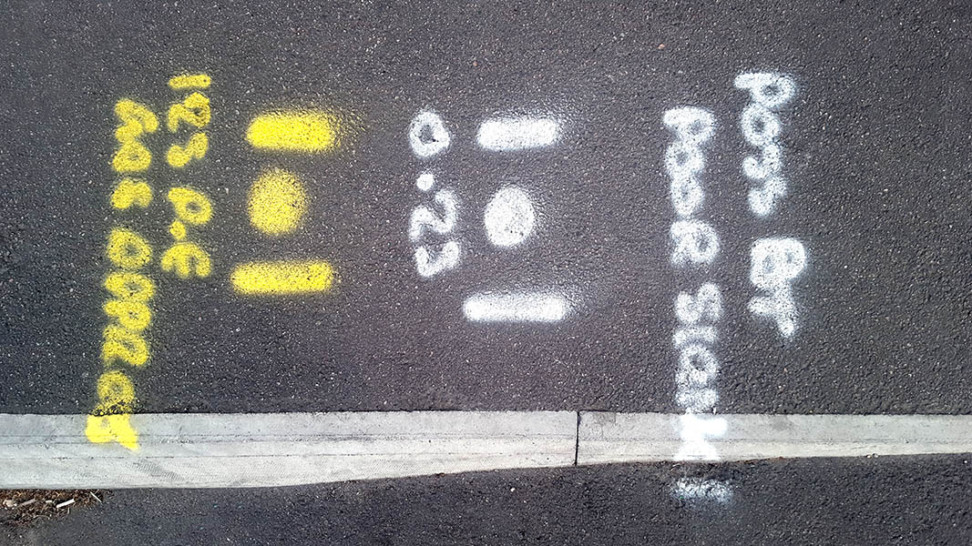 Pavement markings - spray painted squiggles on tarmac - Yellow and white letters and lines