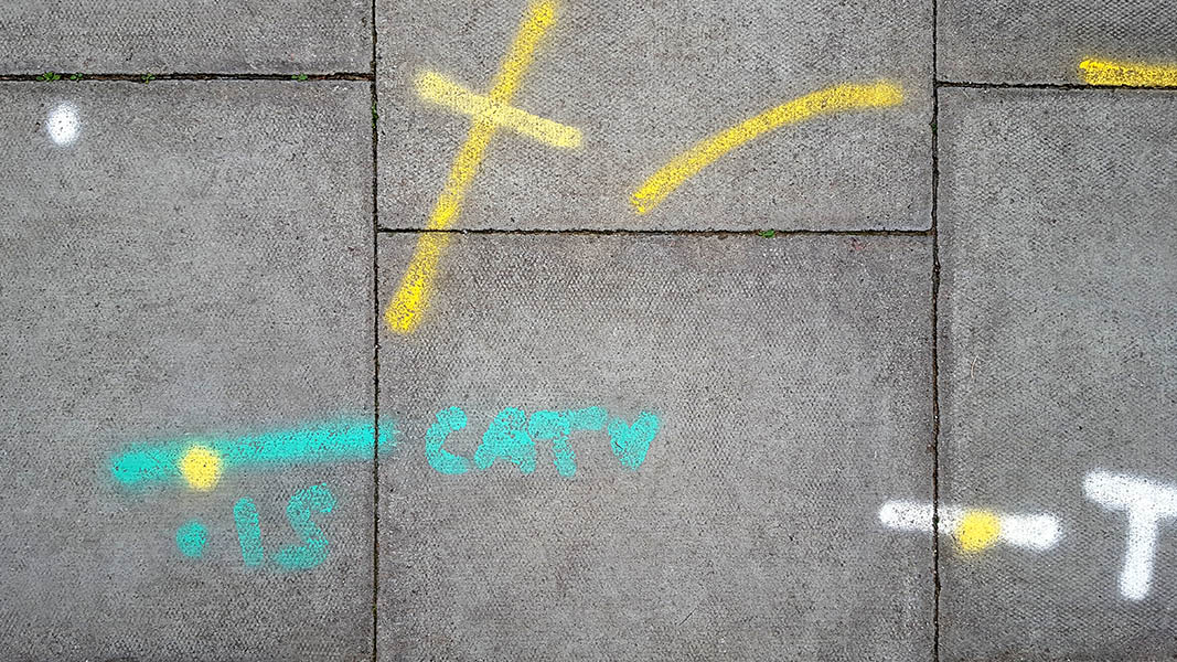 Pavement markings - spray painted squiggles on paving stones - Yellow green and white letters and lines