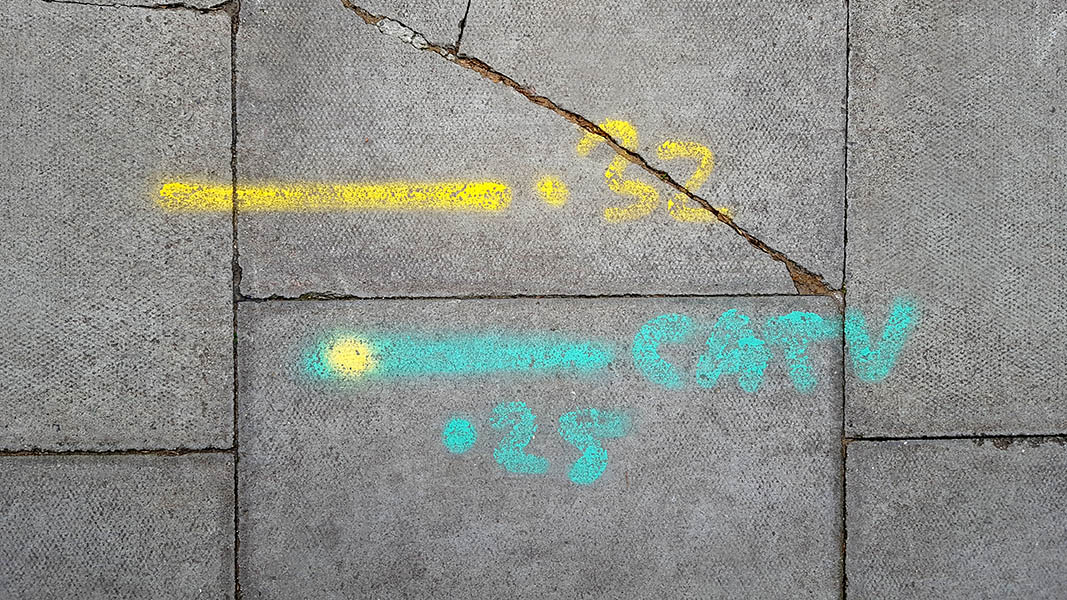 Pavement markings - spray painted squiggles on paving stones - Yellow and green letters and lines