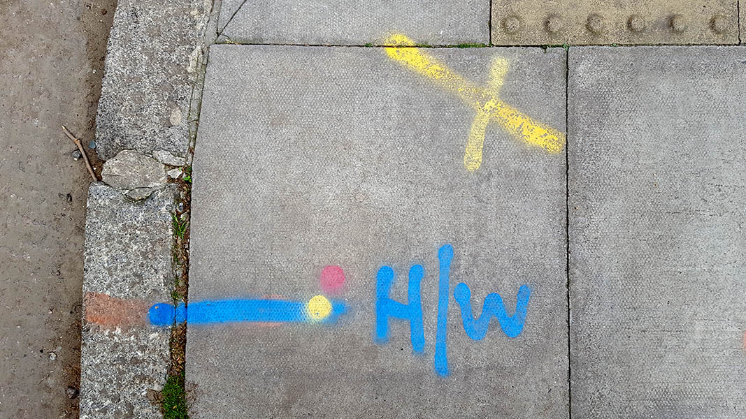 Pavement markings - spray painted squiggles on paving stones - Yellow and blue letters and lines