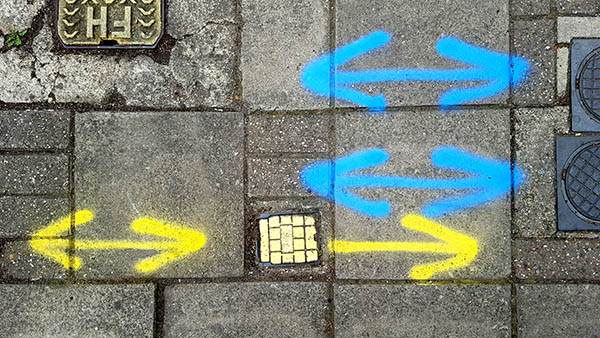Pavement markings - spray painted squiggles on paving stones - Two double sided blue arrows and two yellow