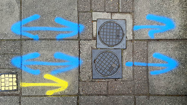 Pavement markings - spray painted squiggles on paving stones - Four blue arrows and one yellow