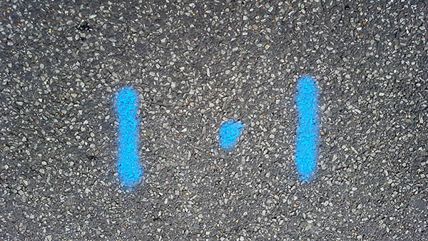 Pavement markings - spray painted squiggles on paving stones - Blue dot flanked by two blue lines