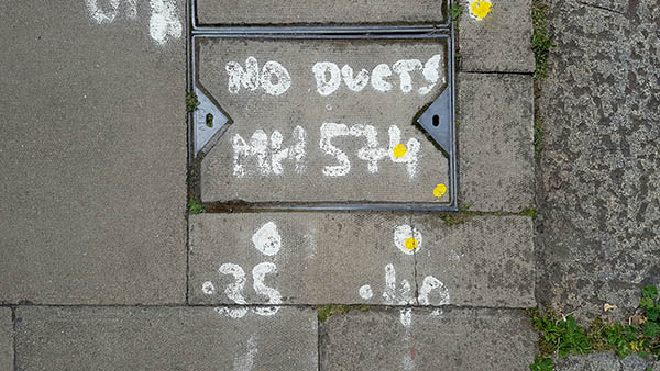 Pavement markings - spray painted squiggles on paving stones - White letters and numbers and yellow dots