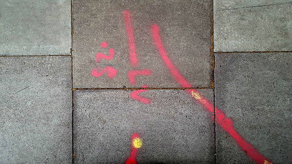 Pavement markings - spray painted squiggles on paving stones - Red lines and letters and numbers