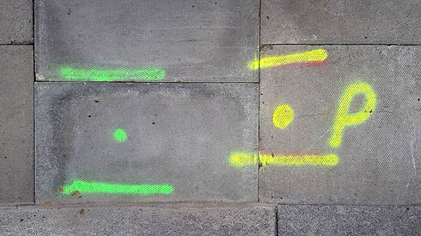 Pavement markings - spray painted squiggles on tarmac - Green and yellow lines and dots with the leter P