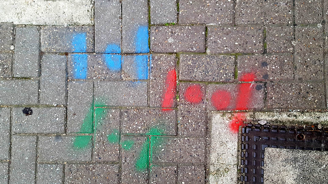 Pavement markings - spray painted squiggles on brick pavement - Dot flanked by vertical lines in three groupings of blue, green and red