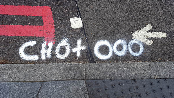 Pavement markings - spray painted squiggles on paving stones - White letters CHO+OOO