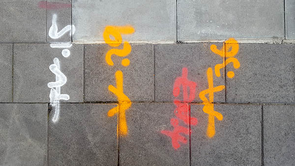 Pavement markings - spray painted squiggles on paving stones - Red orange and white letters and numbers