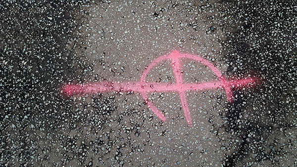 Pavement markings - spray painted squiggles on paving stones - Red lines and three quarter circle