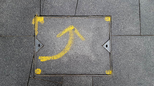 Pavement markings - spray painted squiggles on paving stones - Yellow curved arrow  pointing up flanked by four dots