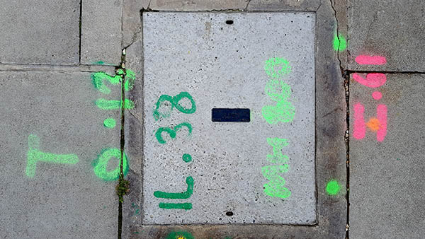 Pavement markings - spray painted squiggles on paving stones - Dark green light green and pink letters and numbers