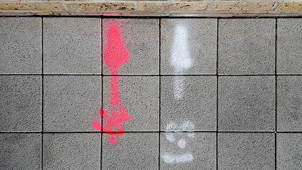Pavement markings - spray painted squiggles on paving stones - Red and white arrows and numbers