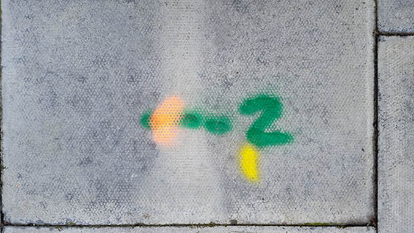 Pavement markings - spray painted squiggles on paving stones -  Green 2 and orange and white markings