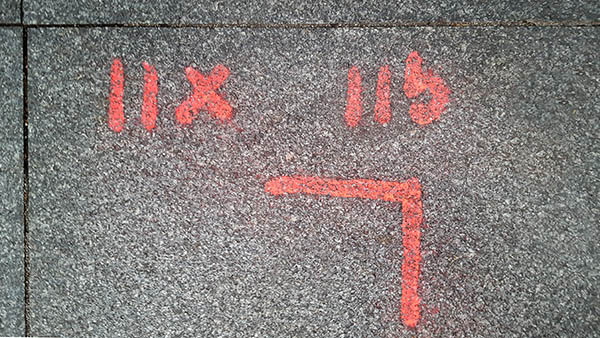 Pavement markings - spray painted squiggles on paving stones - Red lines and numbers