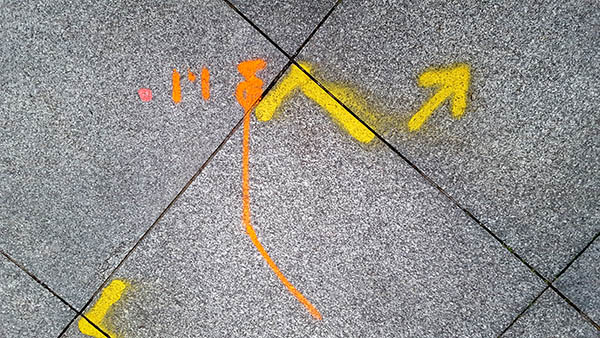 Pavement markings - spray painted squiggles on paving stones -  Orange and yellow markings
