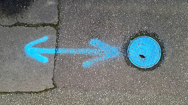 Pavement markings - spray painted squiggles on tarmac - Blue double sided arrow and circle
