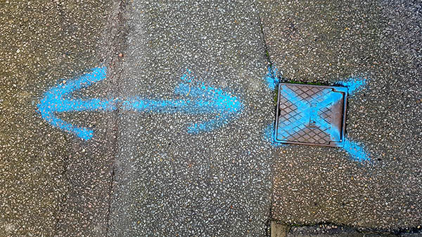Pavement markings - spray painted squiggles on tarmac - Blue double sided arrow and X
