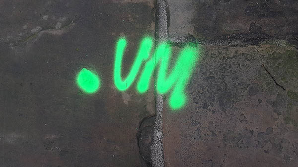Pavement markings - spray painted squiggles on paving stones - Green dot and letters V M