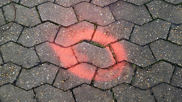 Pavement markings - spray painted squiggles on paving stones - Red circle